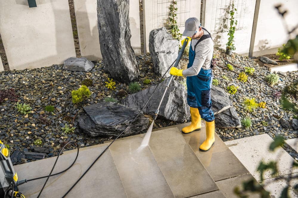 Caucasian Man in Protective Work Wear Cleaning Garden Paths with Pressure Washer