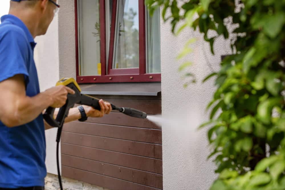 a man washing wall with high pressure washing machine