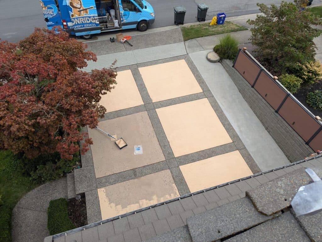 Lyonridge Property Services technician rolling concrete sealer onto a driveway in Port Coquitlam